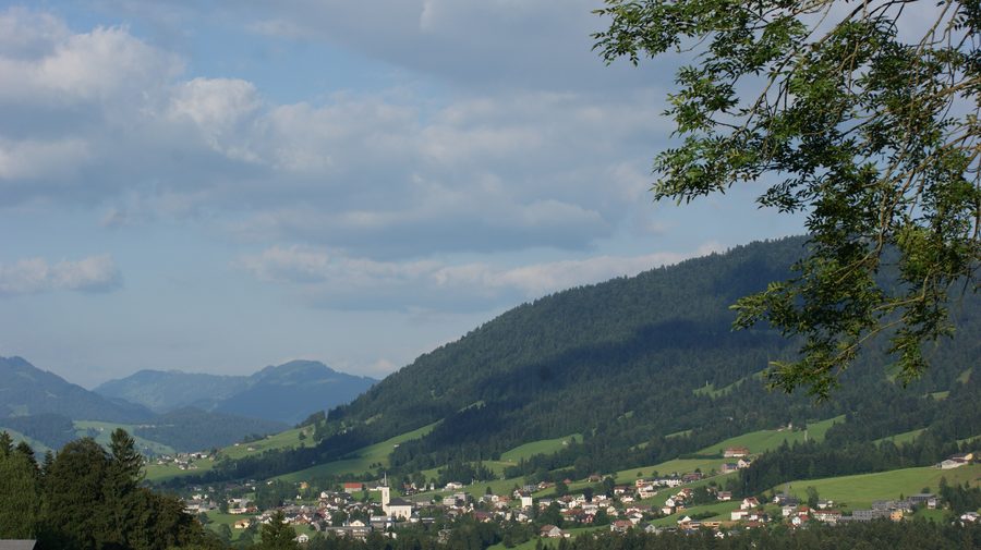 Blick auf das Ortszentrum von Alberschwende mit dem Bregenzerwald im Hintergrund