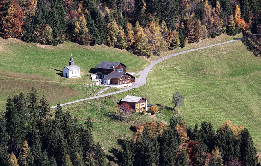 Luftbild der Benediktskapelle und landwirtschaftlicher Gebäude im Ortsteil Bischa der Gemeinde Dünserberg